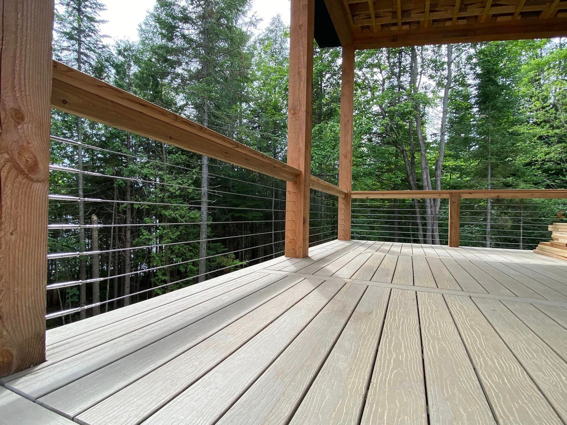Une terrasse en bois avec une balustrade en métal et des arbres en arrière-plan.