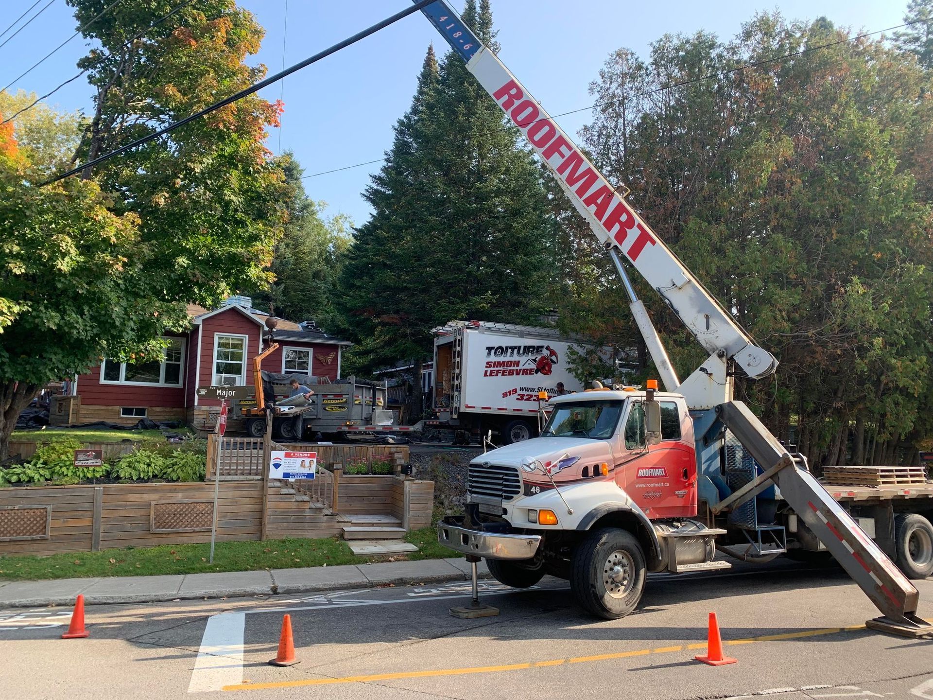 Un camion Roofmart est garé sur le bord de la route.