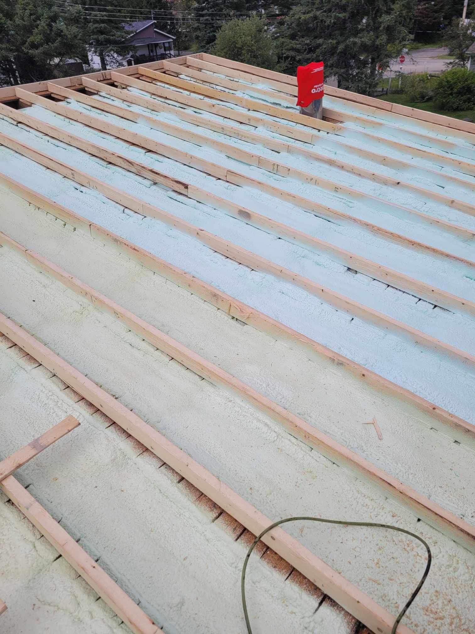 Un toit est en cours de construction avec des poutres en bois et de la mousse.