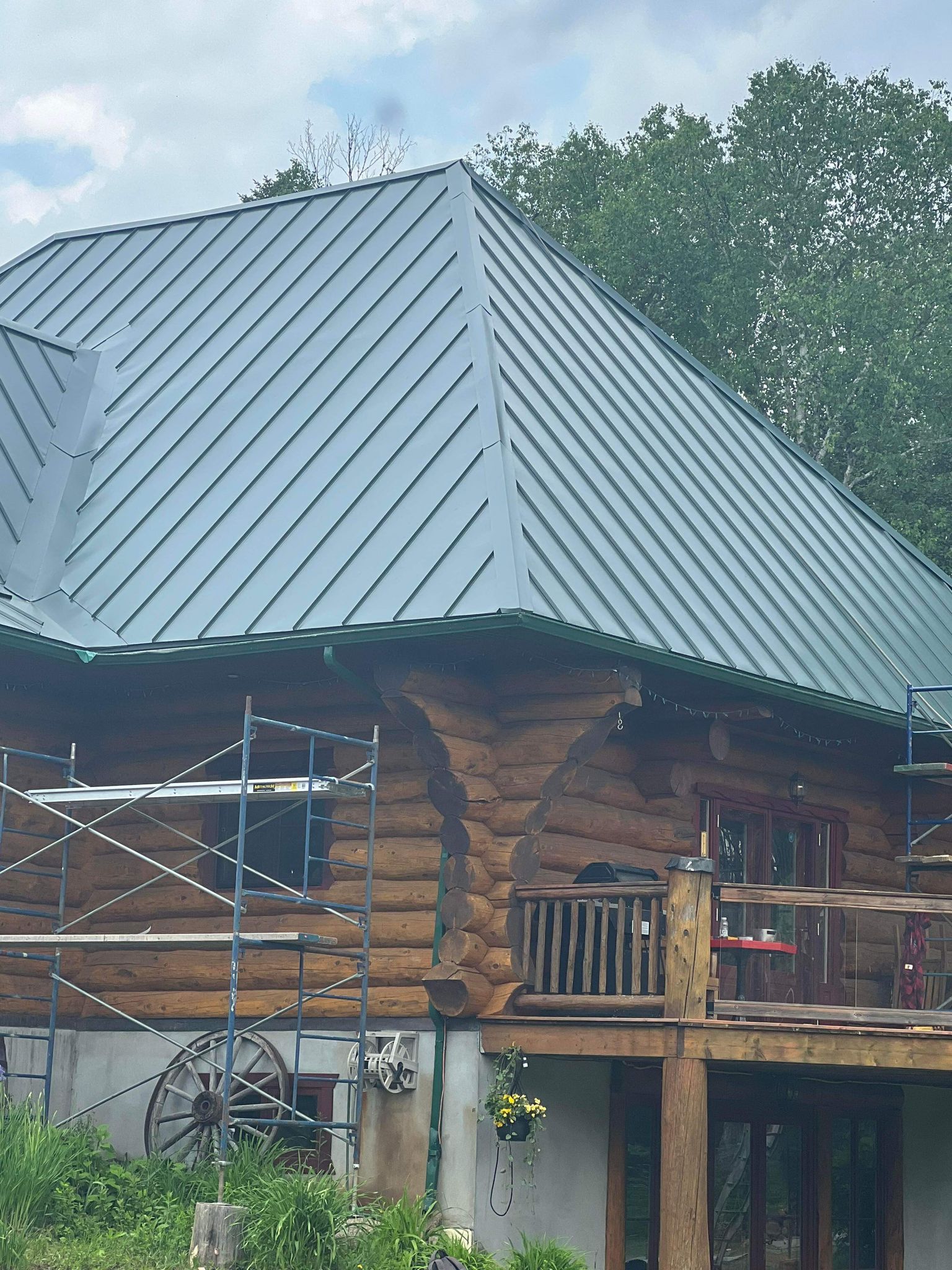 Une cabane en rondins avec un toit en métal et une terrasse.