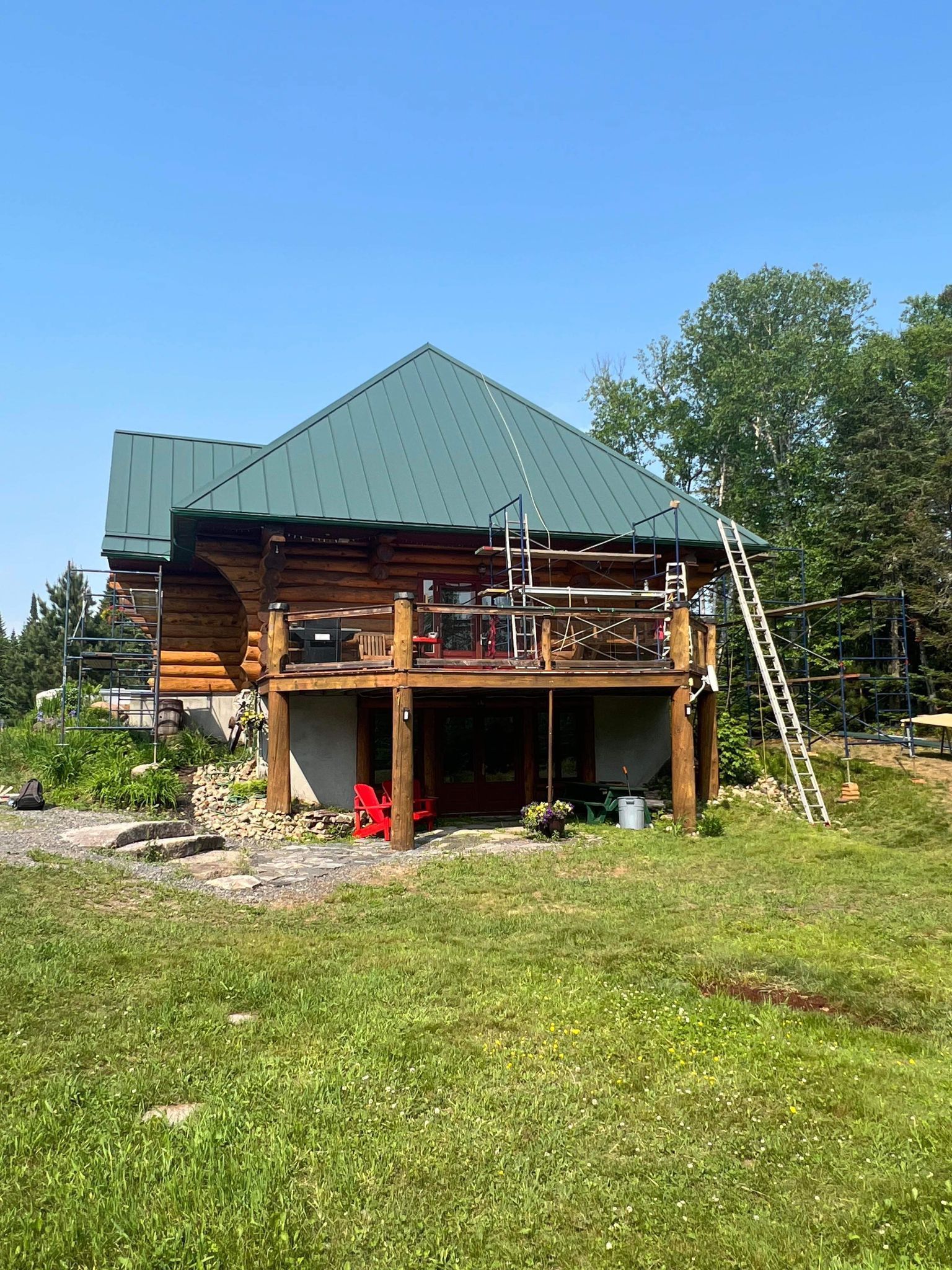 Une cabane en rondins avec un toit vert est située au milieu d'un champ herbeux.