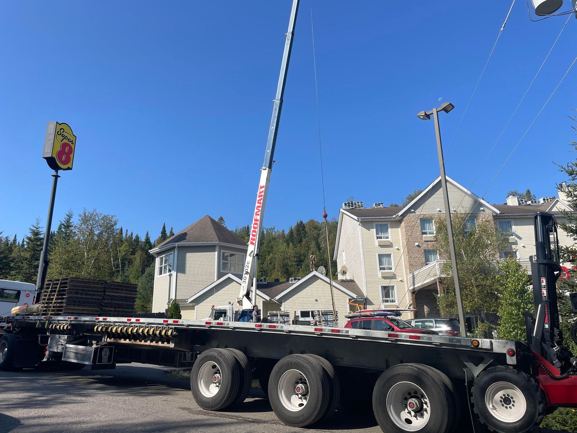 Un semi-camion avec une grue à l'arrière est garé devant un restaurant super 8.