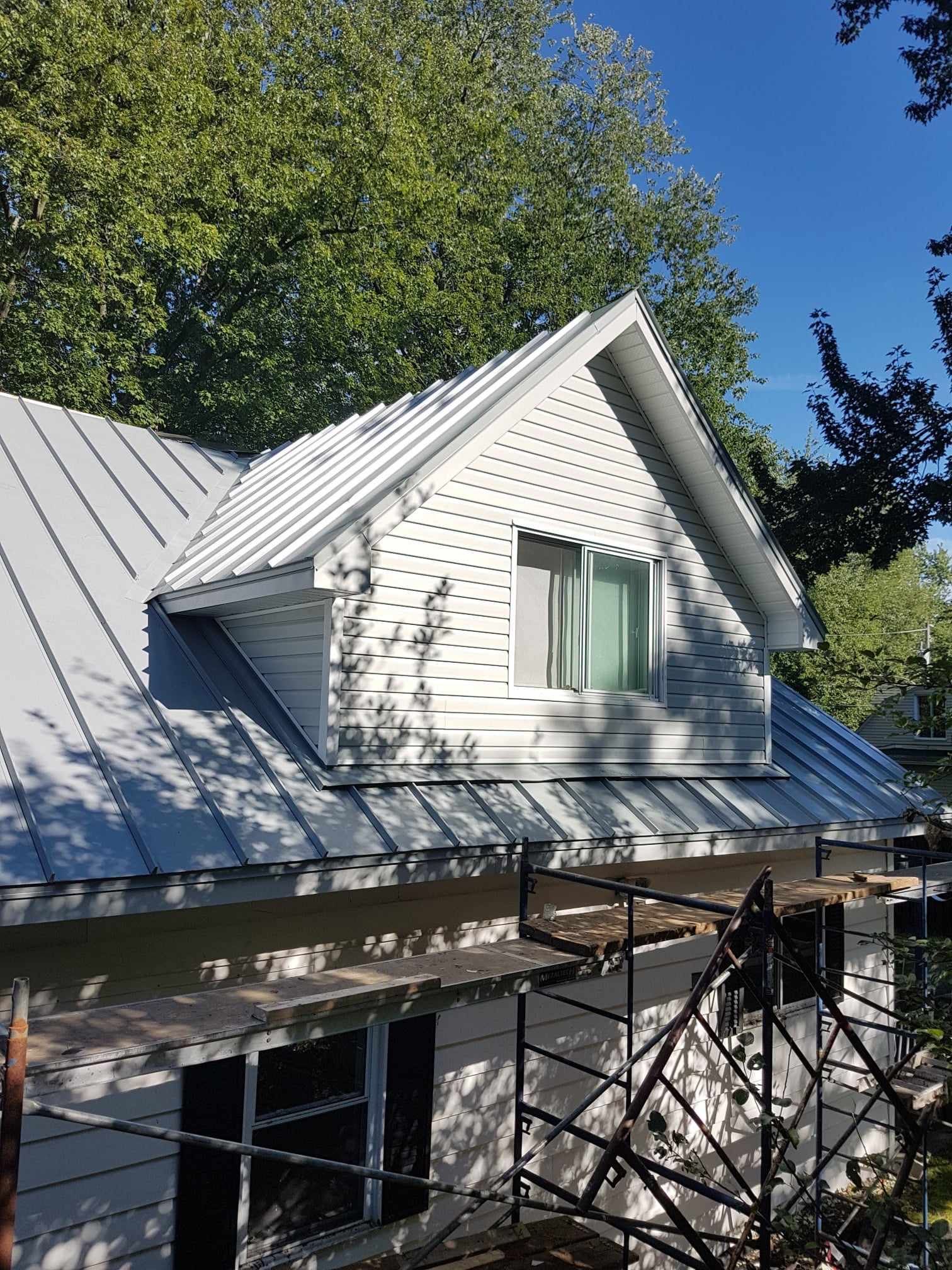 Une maison blanche avec un toit en métal et une fenêtre.