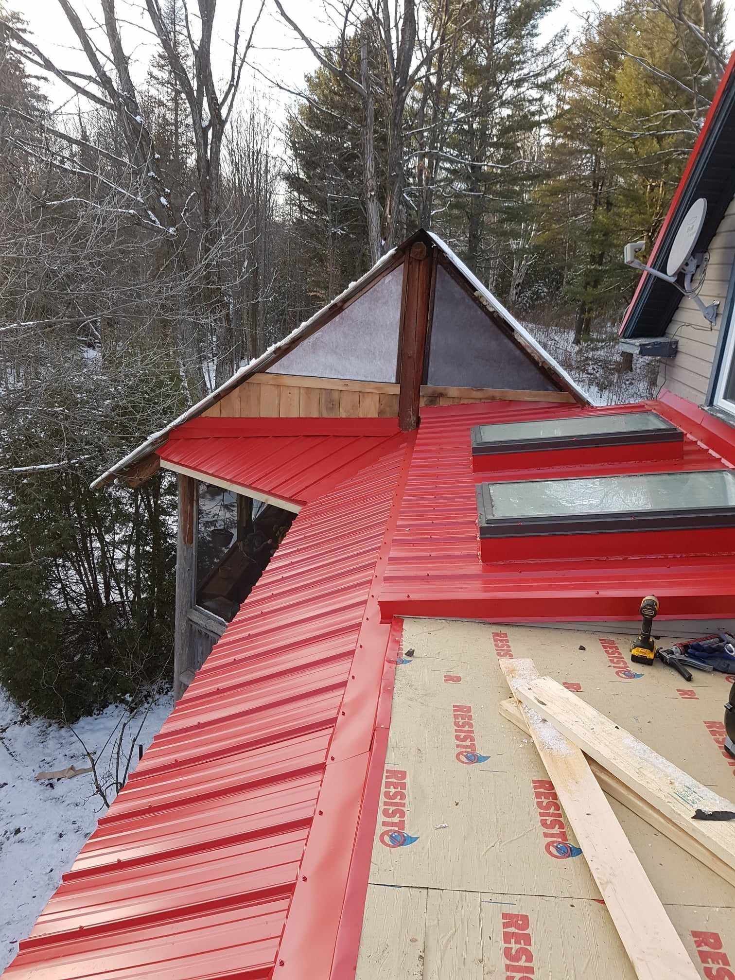 Un toit en métal rouge est en train d'être installé sur une maison.