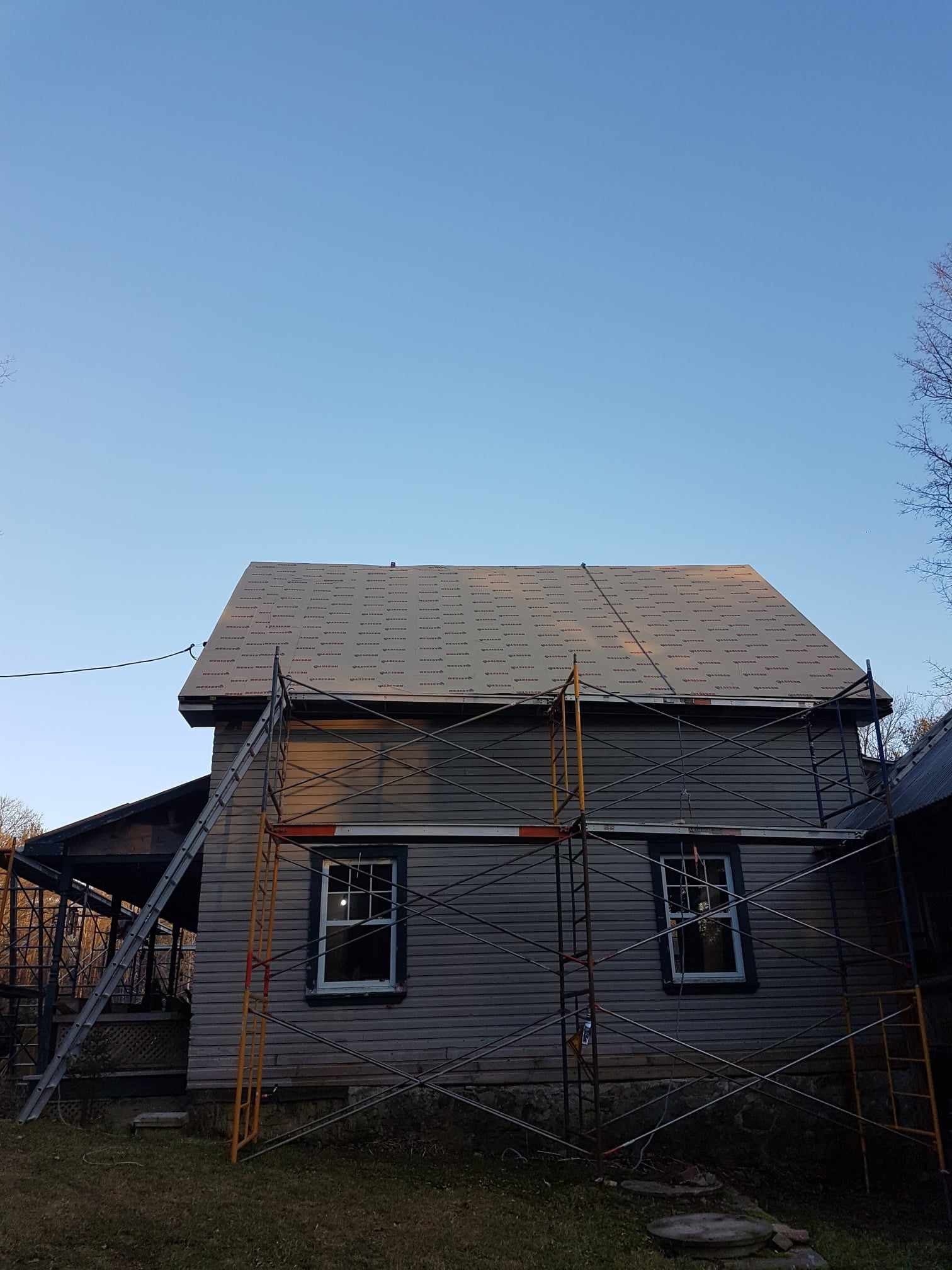 Une maison avec un toit en cours de réparation avec des échafaudages autour.