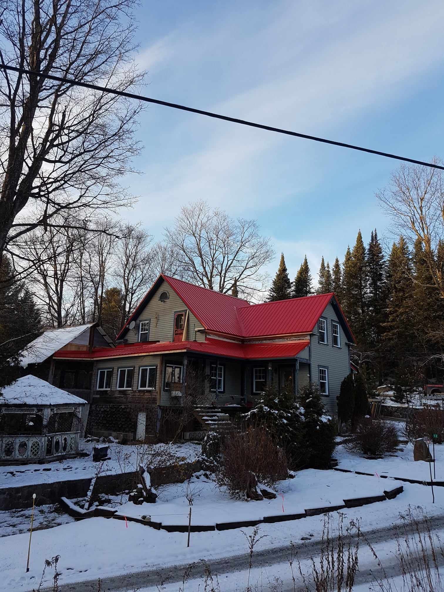 Une maison au toit rouge est entourée de neige et d'arbres.