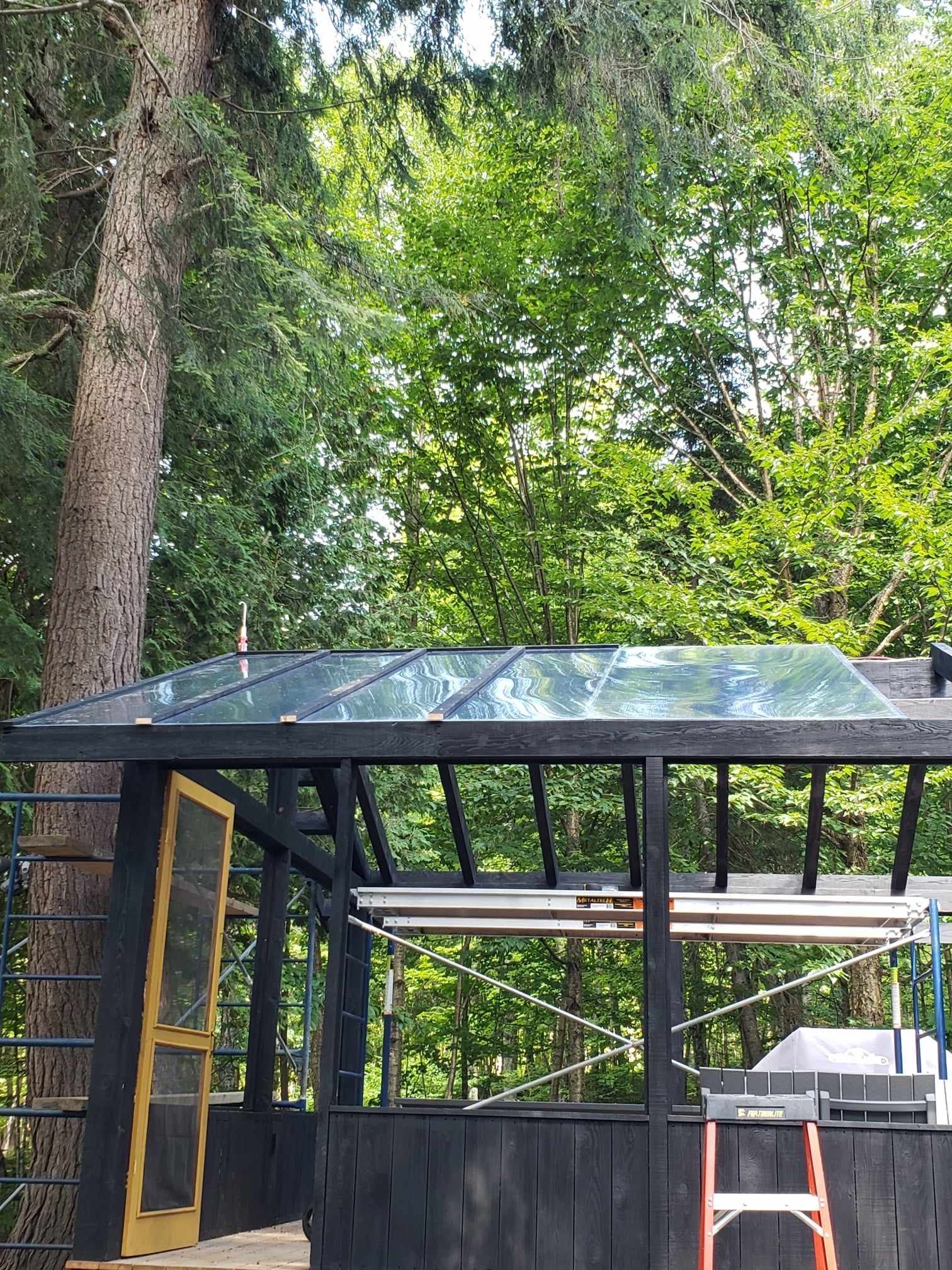 Une serre avec un toit en verre est en construction dans les bois.