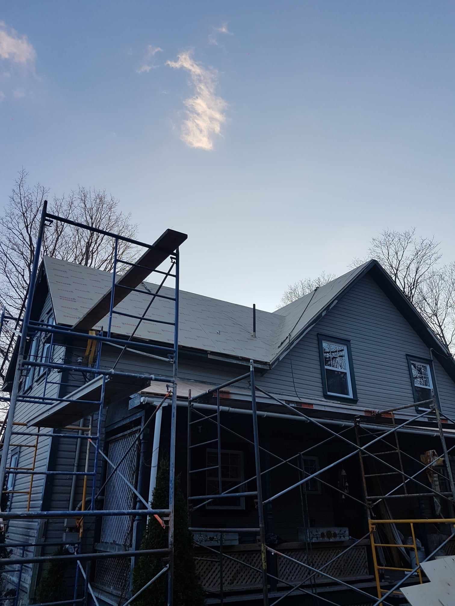 Une maison avec des échafaudages autour et un ciel bleu en arrière-plan.