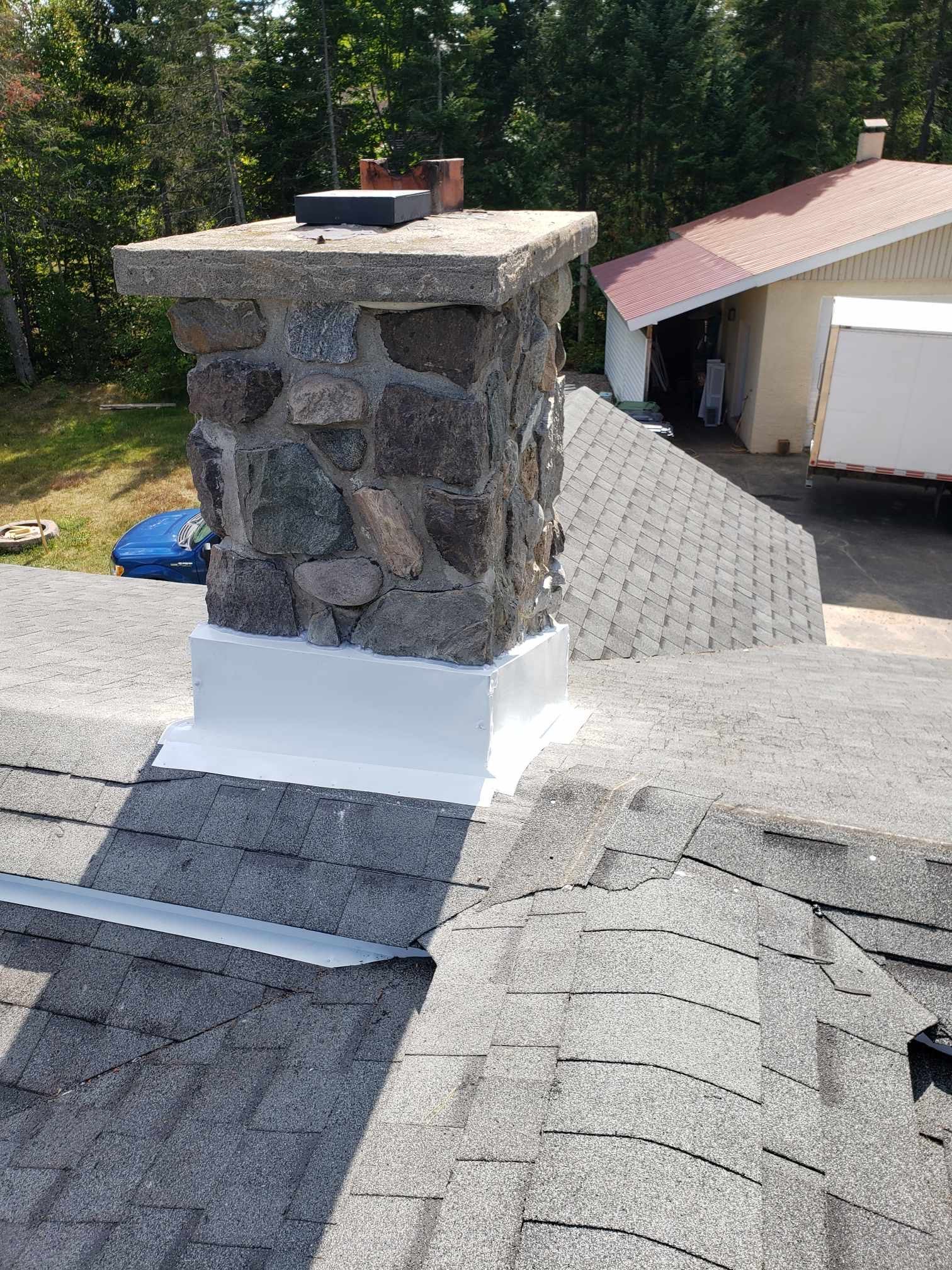 Une cheminée est située au sommet d'un toit à côté d'une maison.