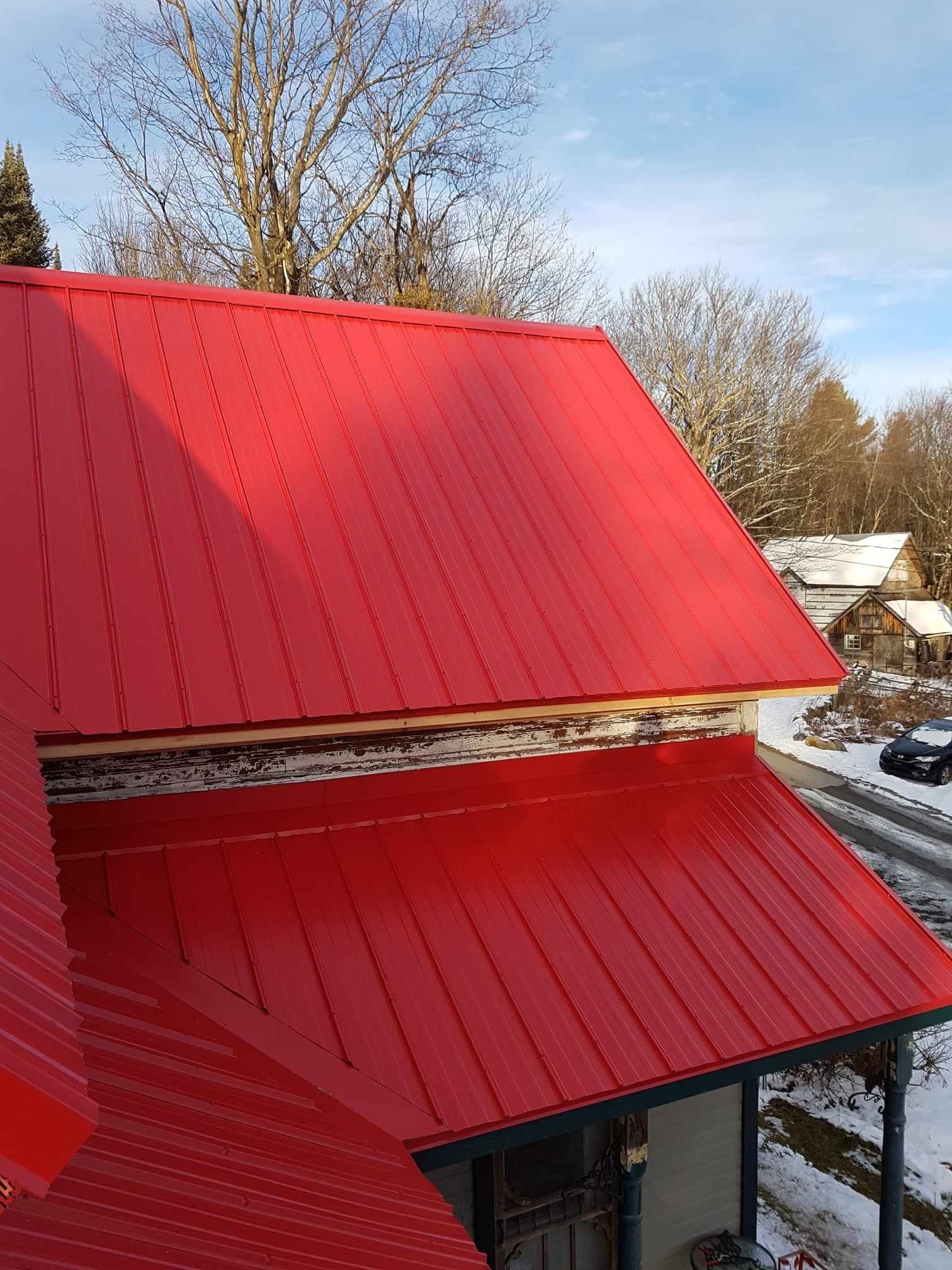 Un toit en métal rouge repose sur une maison.