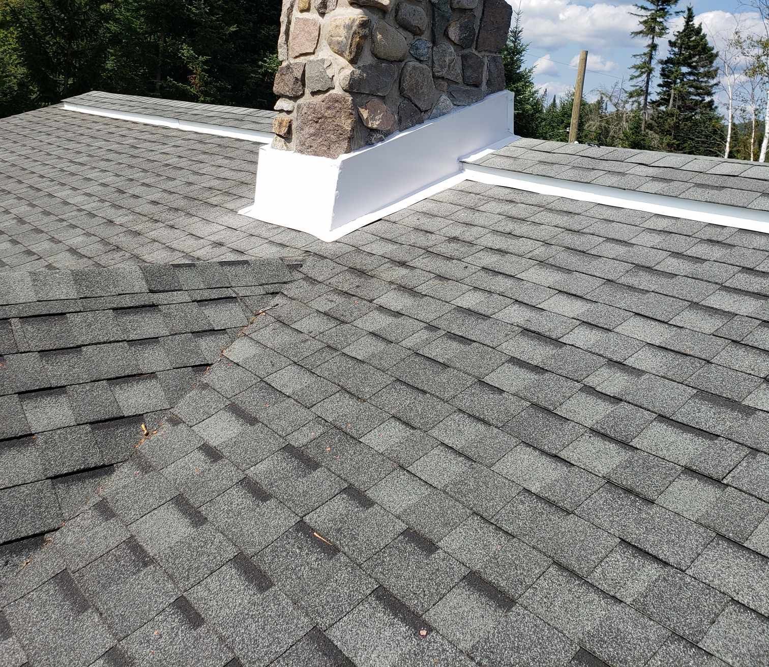 Un toit avec des bardeaux et une cheminée au-dessus.