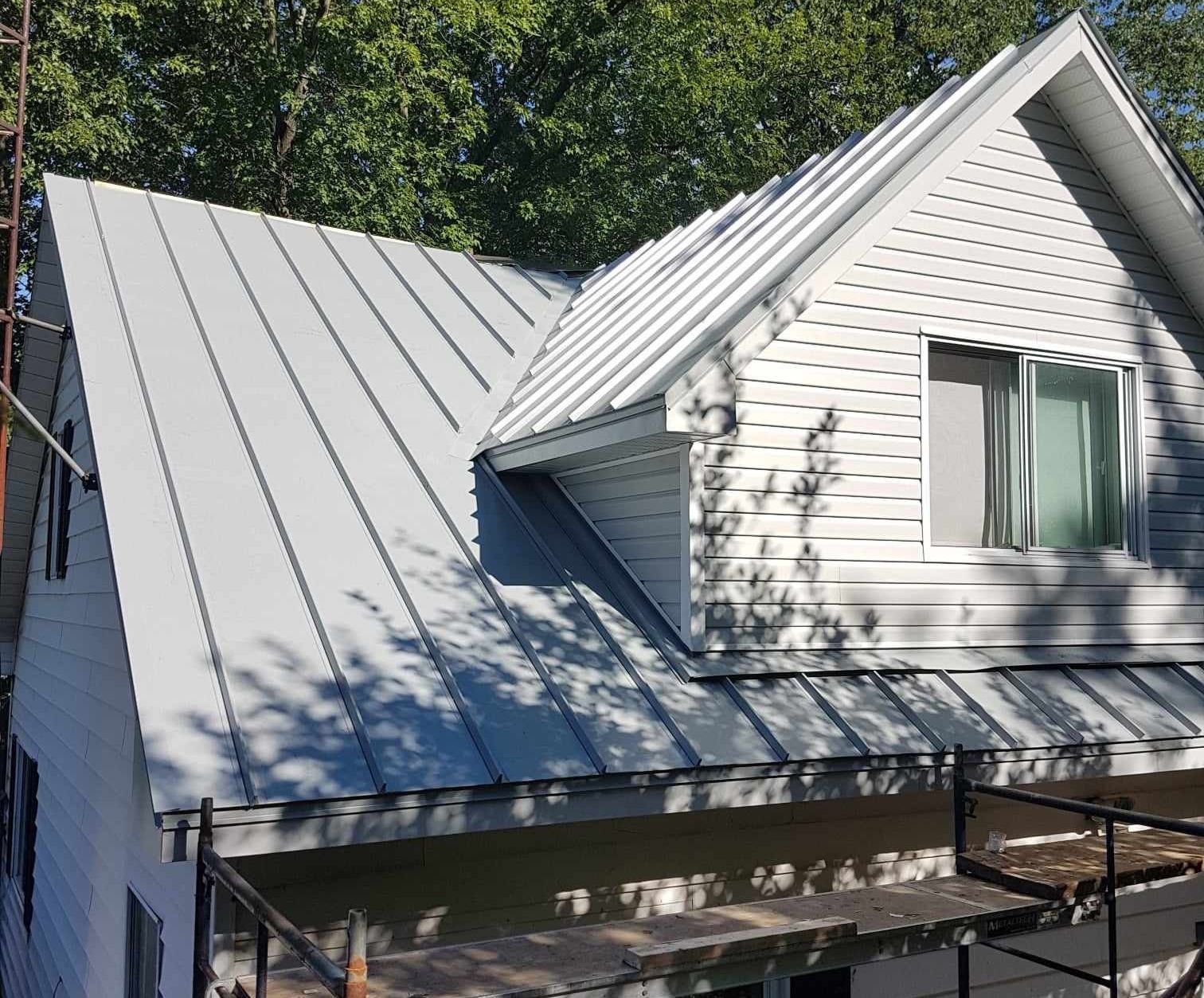 Une maison blanche avec un toit en métal est en cours de rénovation.