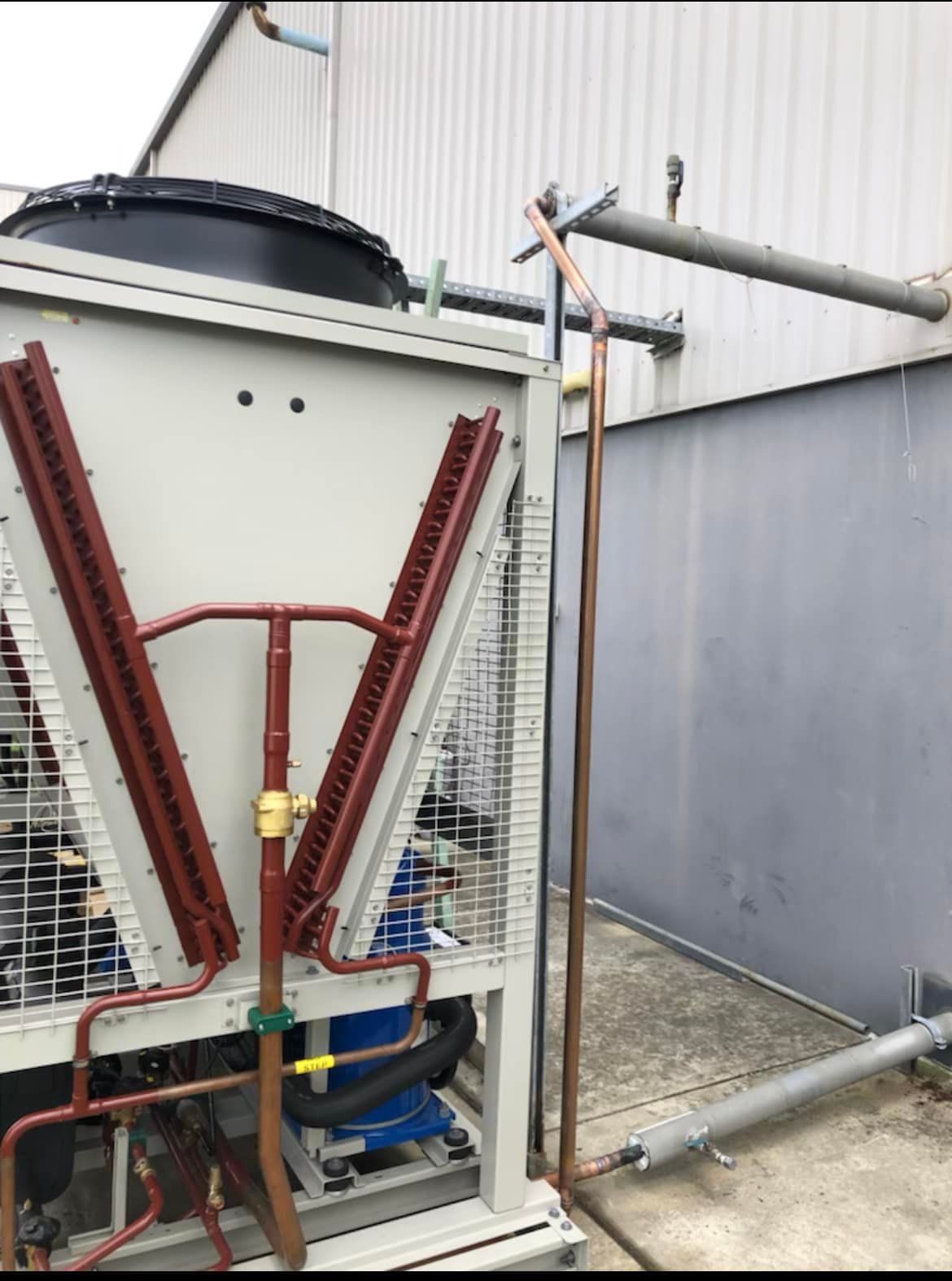 A large machine with pipes attached to it is sitting outside of a building — Industrial Air Conditioning Hunter Valley