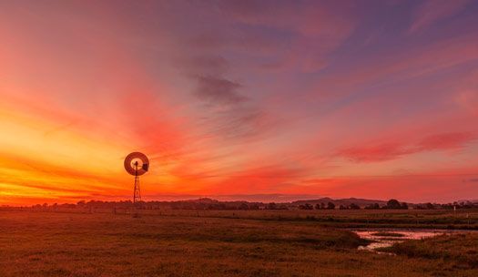 There is a windmill in the middle of a field at sunset — Air Conditioning Installer Maitland