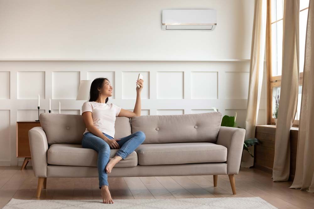 Woman Turning Off The Air Conditioner In The Room — Split System Air Conditioning Hunter Valley