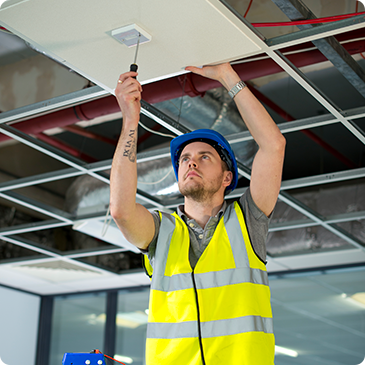 A man is working on a ceiling with a screwdriver.