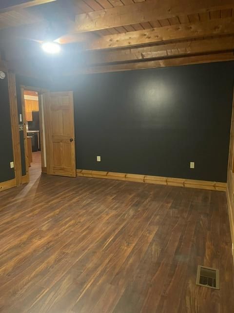 An empty room with hardwood floors and black walls.