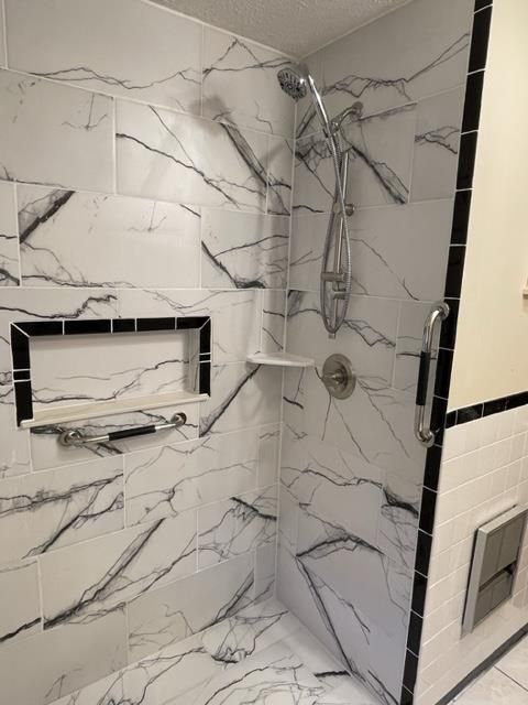 A bathroom with black and white tiles and a walk in shower