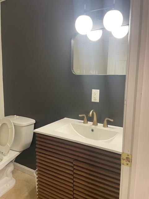 A bathroom with a toilet , sink and mirror.