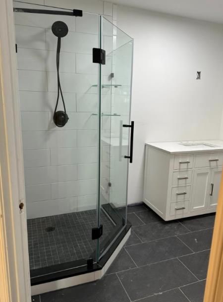 A bathroom with a walk in shower and a sink.