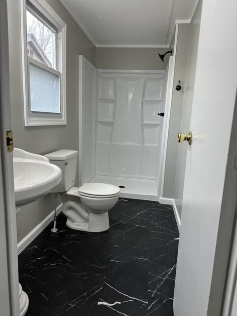 A bathroom with a toilet , sink and shower.