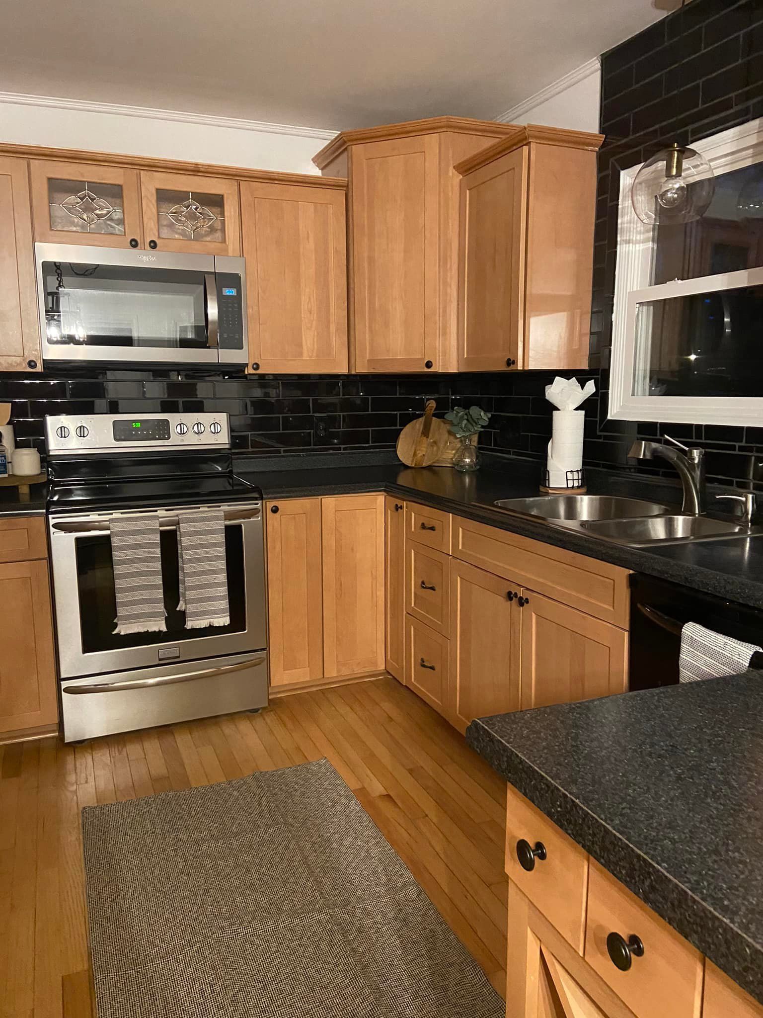 a kitchen with white cabinets , wooden counter tops , stainless steel appliances and a large island .