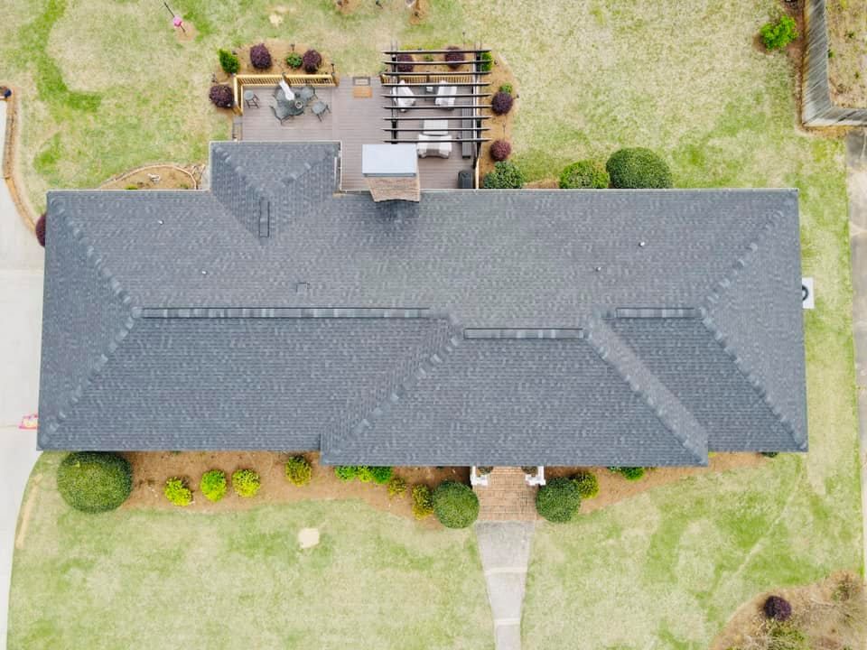 Overhead view of a house with a gray roof, lawn, patio, and landscaping.