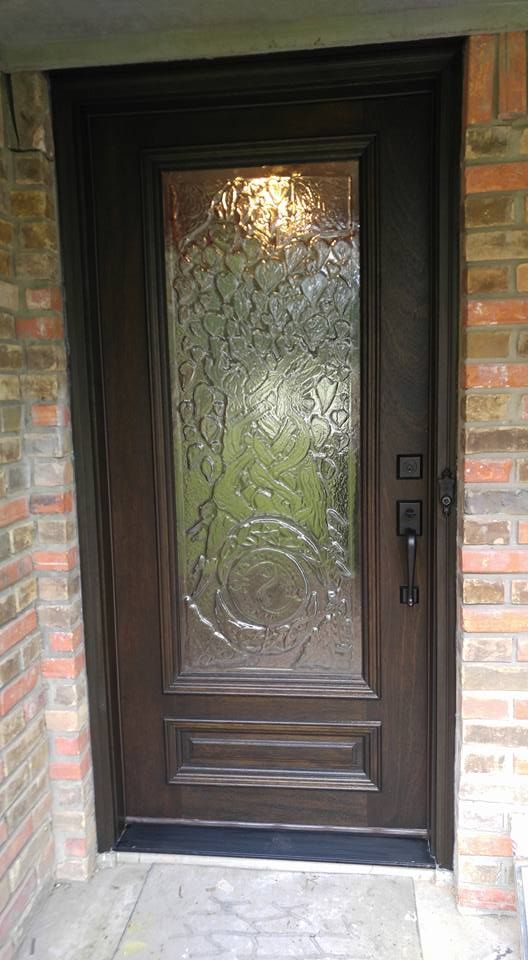 A wooden door with a glass window is on a brick wall.