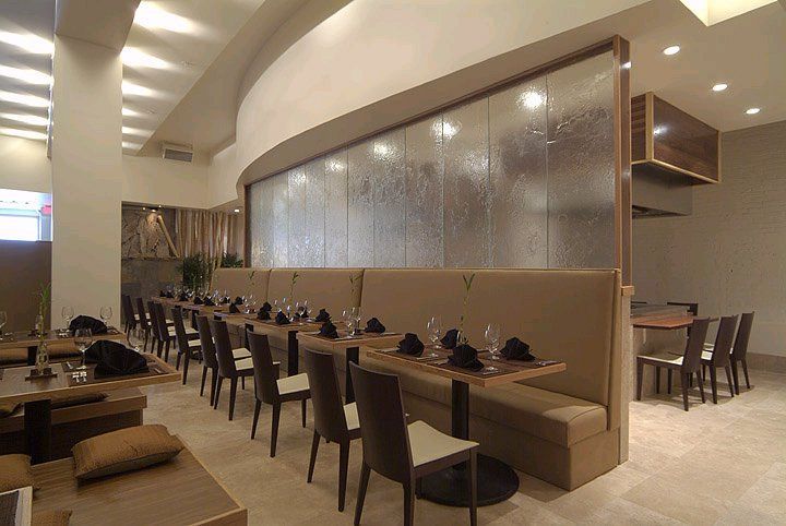 A restaurant with tables and chairs and a waterfall in the background.