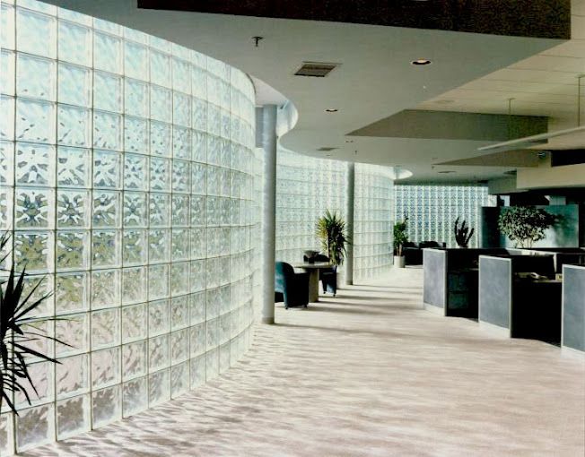 A hallway with cubicles and a curved wall made of glass blocks