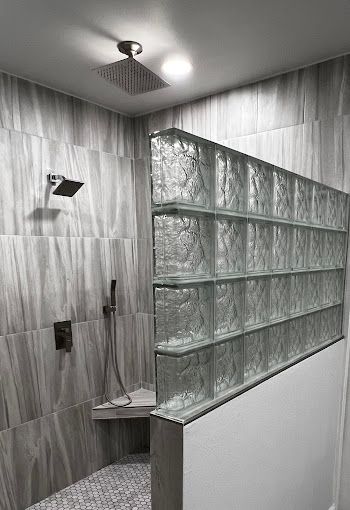 A shower with a glass block wall and a shower head.