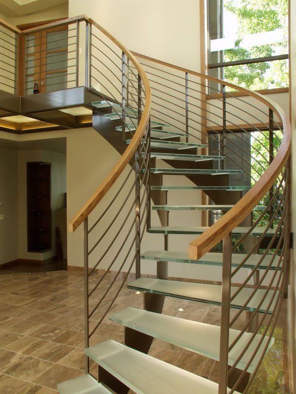A curved staircase with glass steps and a wooden railing