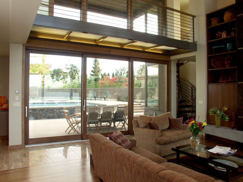 A living room with a couch , chairs , and sliding glass doors leading to a patio.