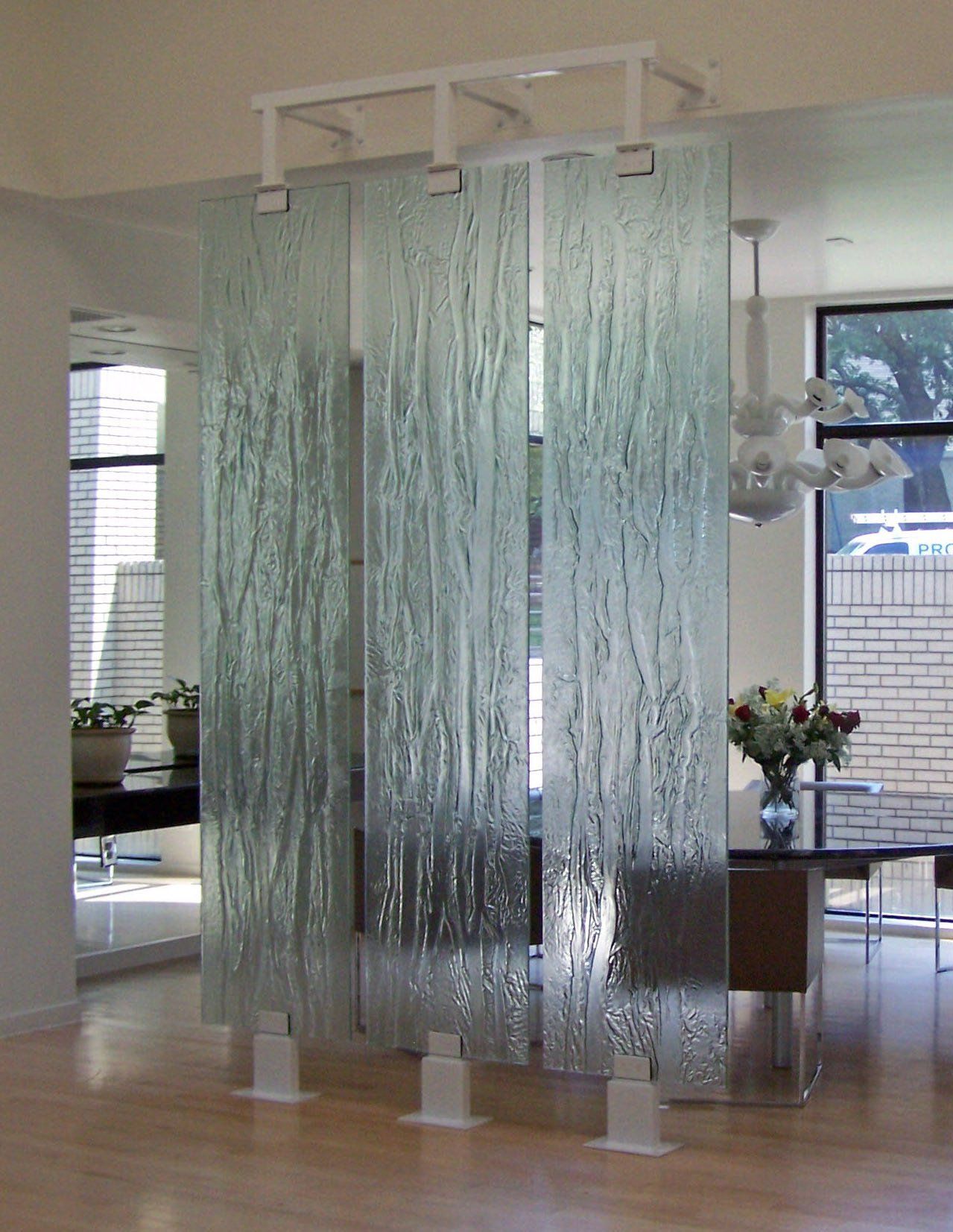 A dining room with a table and chairs separated by glass dividers