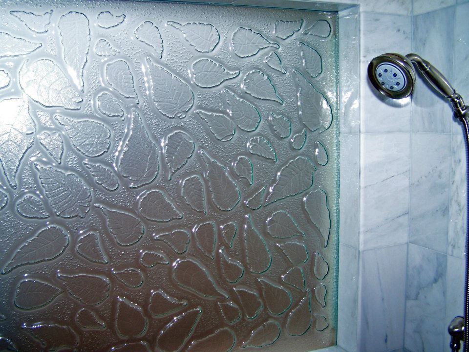 A shower head in a bathroom next to a glass wall