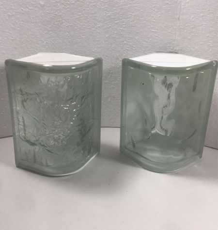 Two clear glass bricks are sitting on top of a white table.