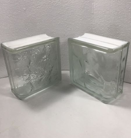 Two clear glass bricks are sitting on top of a white table.