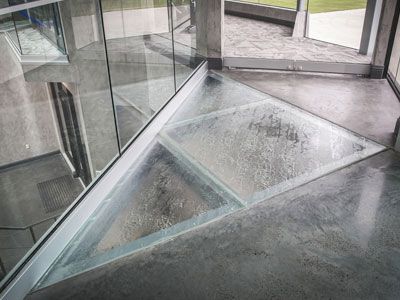 A staircase with a glass railing and a concrete floor in a building.