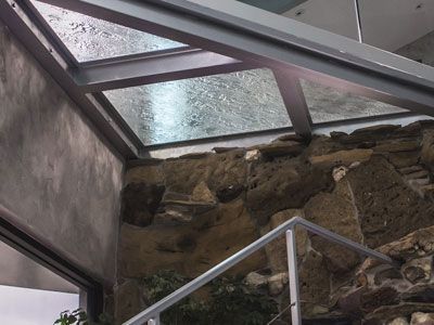 A staircase with a glass roof and a stone wall.