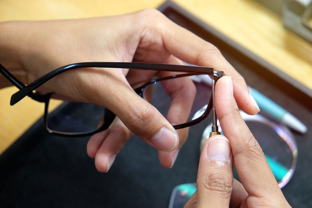 A person is holding a pair of glasses in their hands.