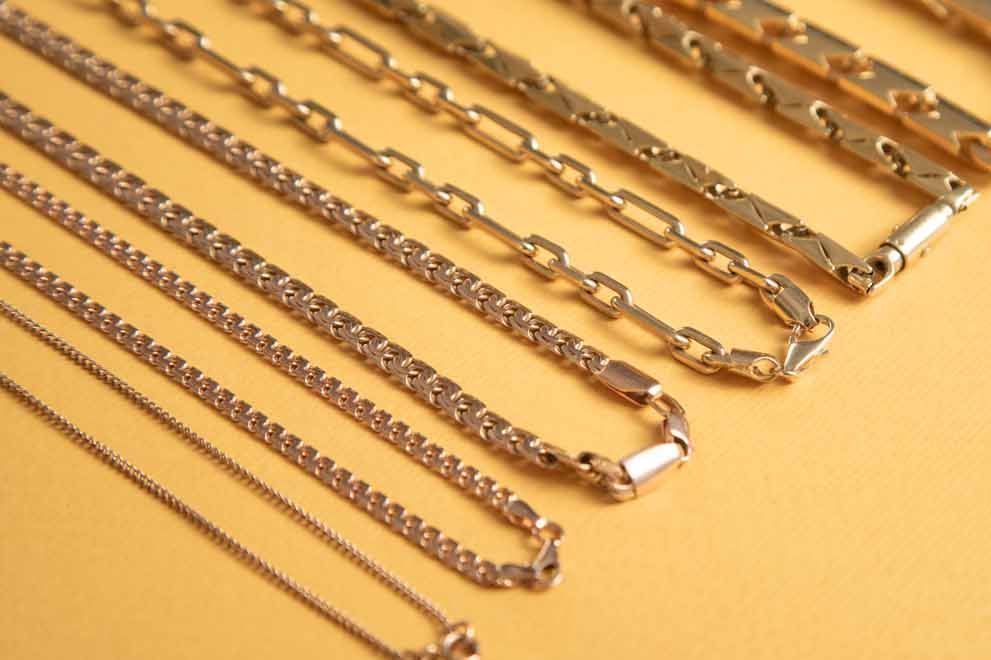 A bunch of different types of chains are lined up on a table