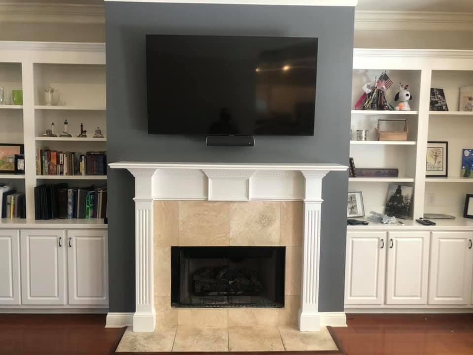 Fireplace flanked by white bookshelves, gray wall, and large black TV.