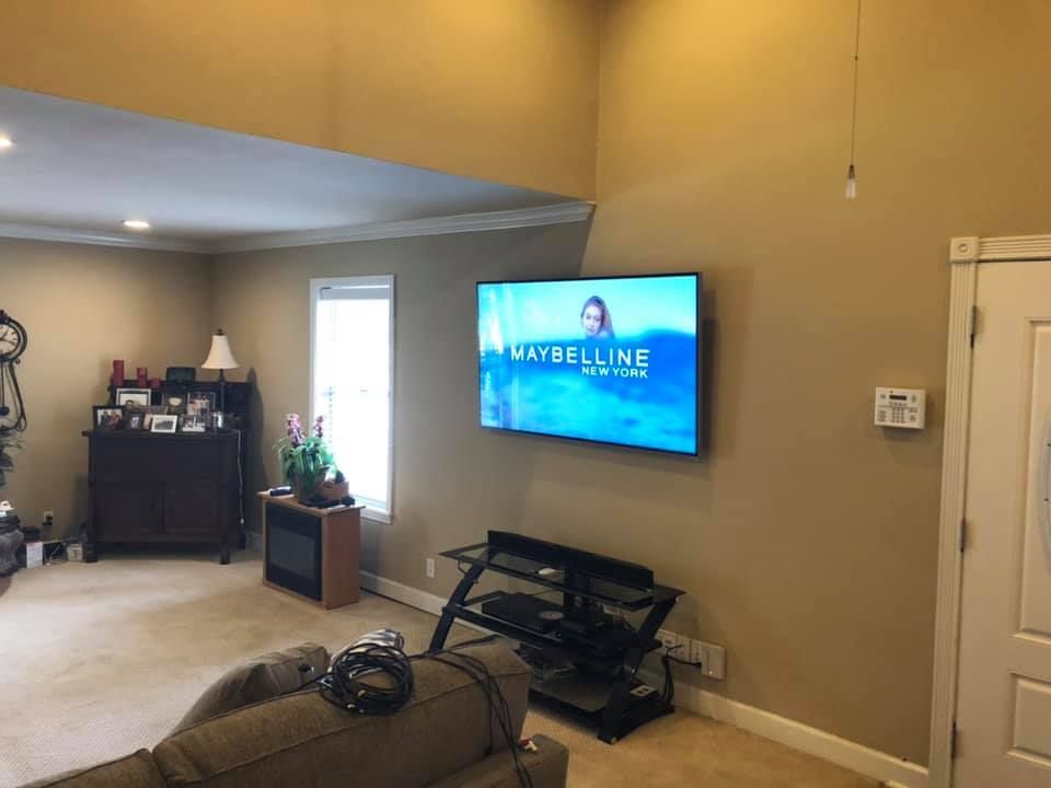 Living room with TV on wall, tan walls, dark cabinet, window, couch.