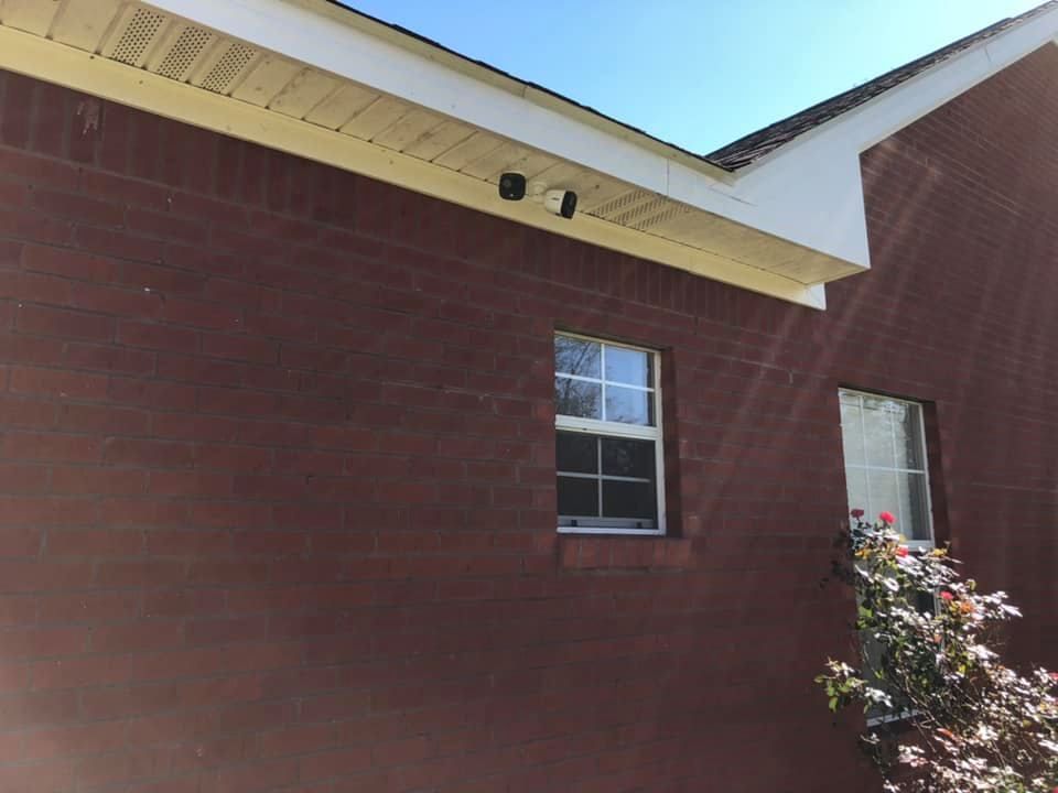 Red brick building with two windows and security cameras under the roof.