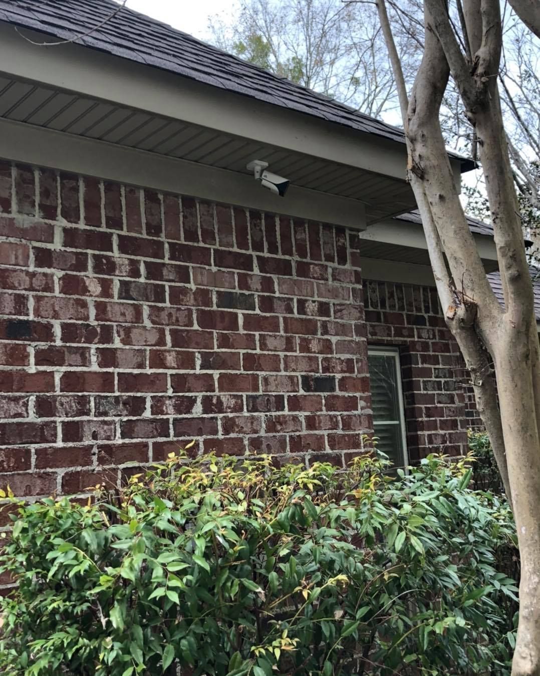 Brick building exterior with a security camera under the roof overhang.