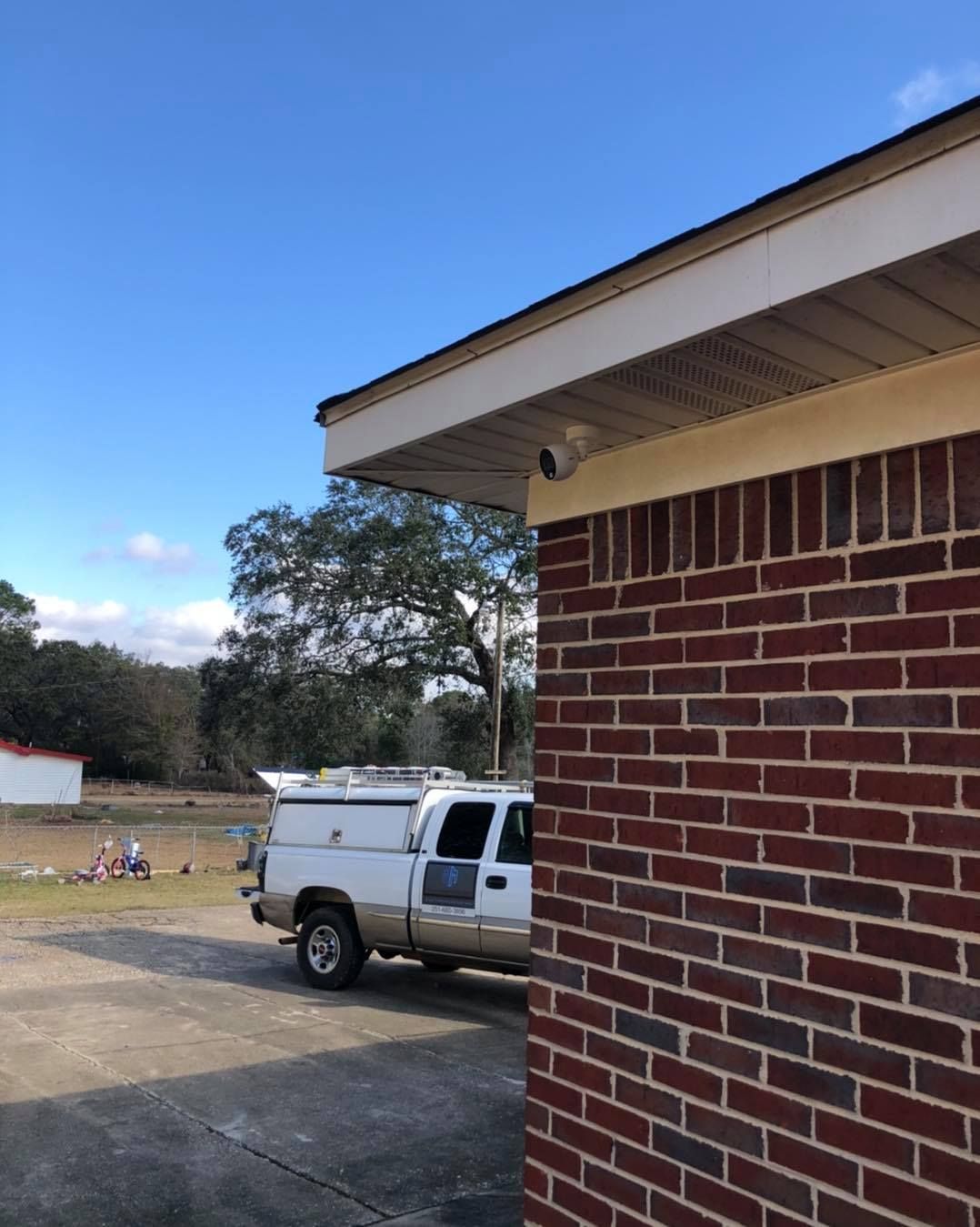 Brick building exterior with a white truck parked nearby under a clear blue sky.