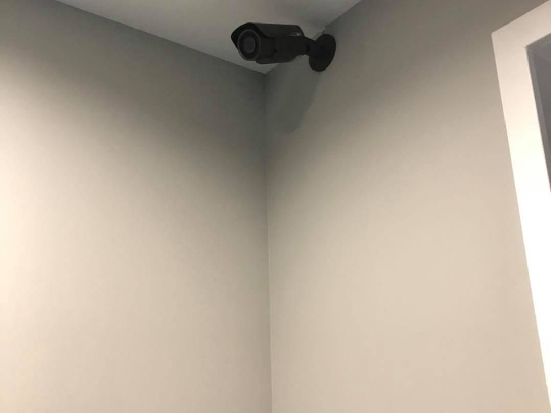 Security camera mounted in a corner of a room, pointed downwards.