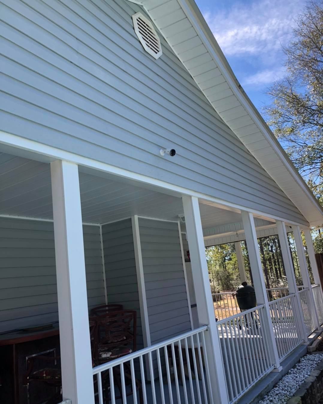 Light blue house with white porch. Cloudy sky.