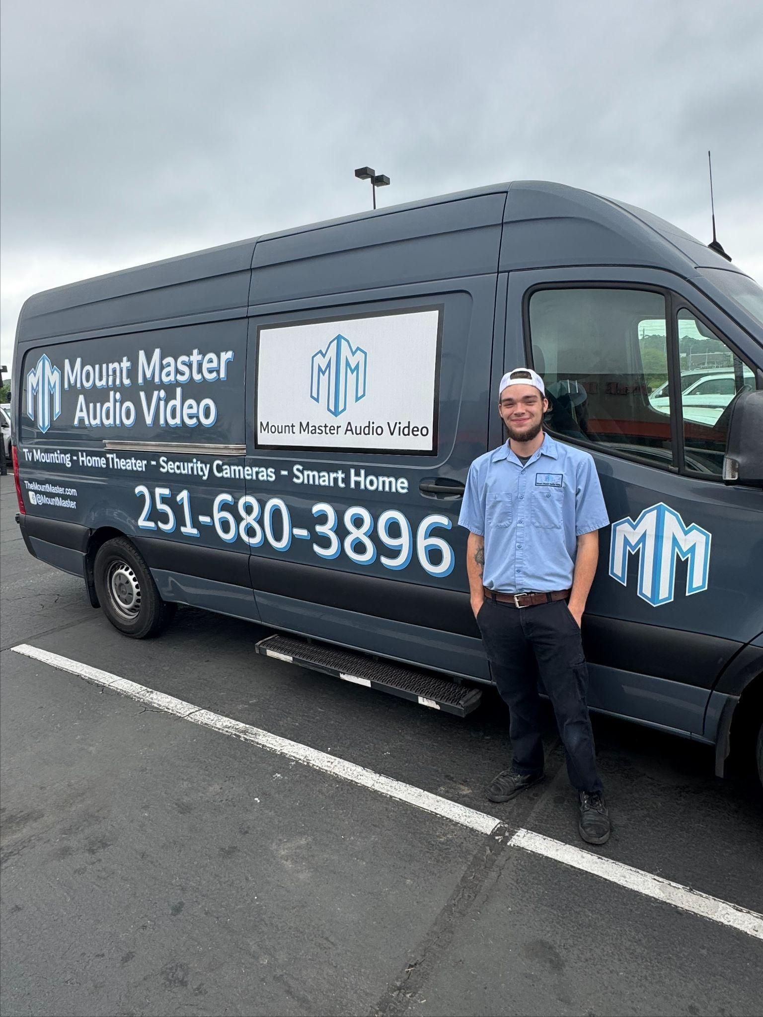 Man in uniform stands beside a dark van with