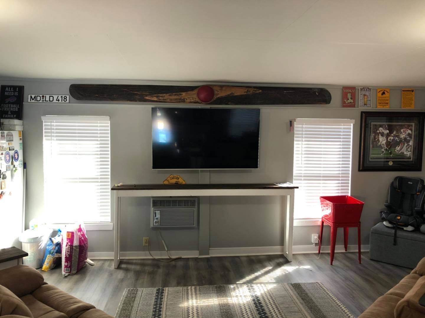 Living room with TV on wall, console table, windows, and decorative items.